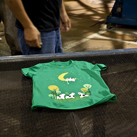 The ink is cured by sending the shirt through an industrial dryer. Here is a Threadless design on the conveyer belt, ready to be wet no more.
